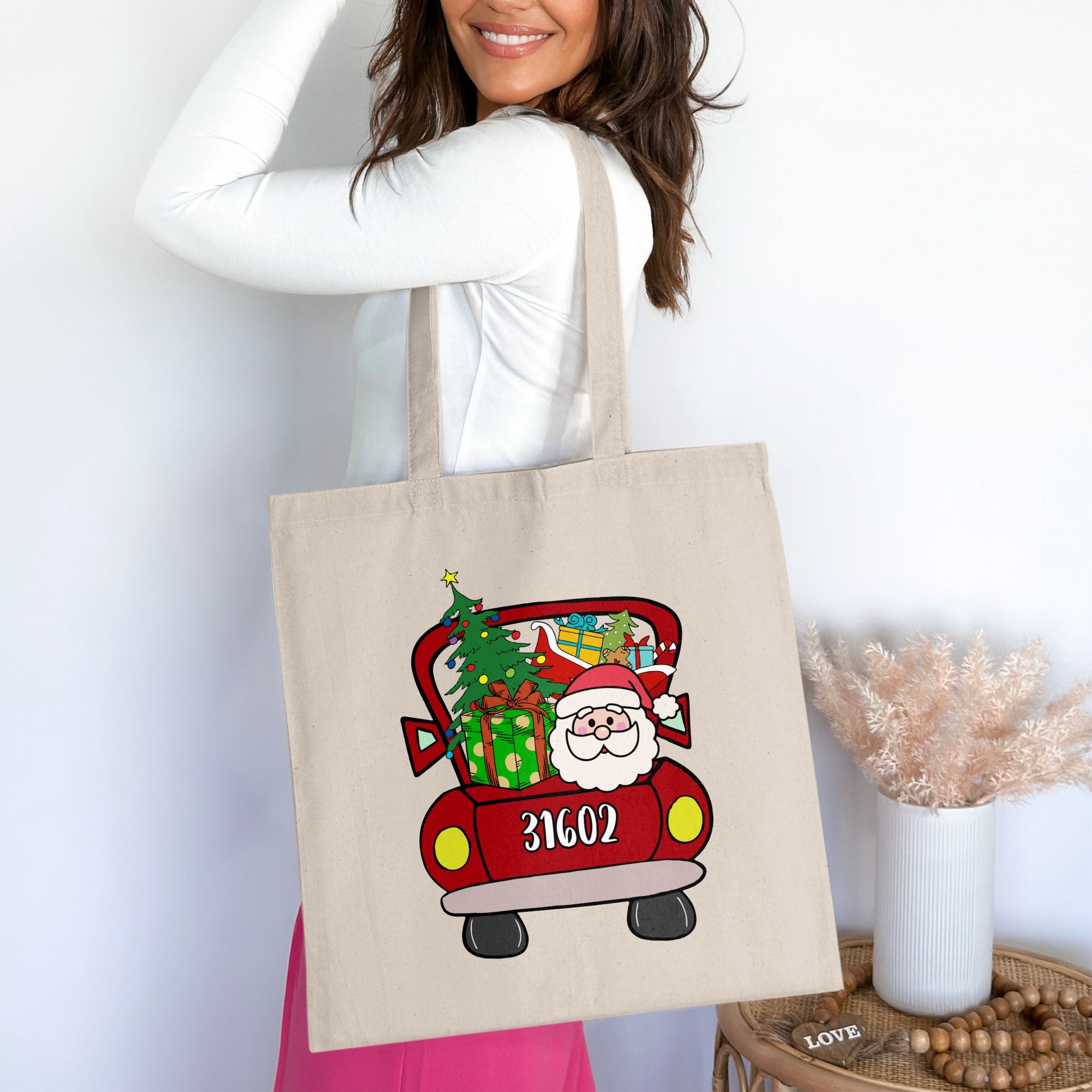 Tote bag with a red cartoon truck carrying Santa, presents, and a Christmas tree.