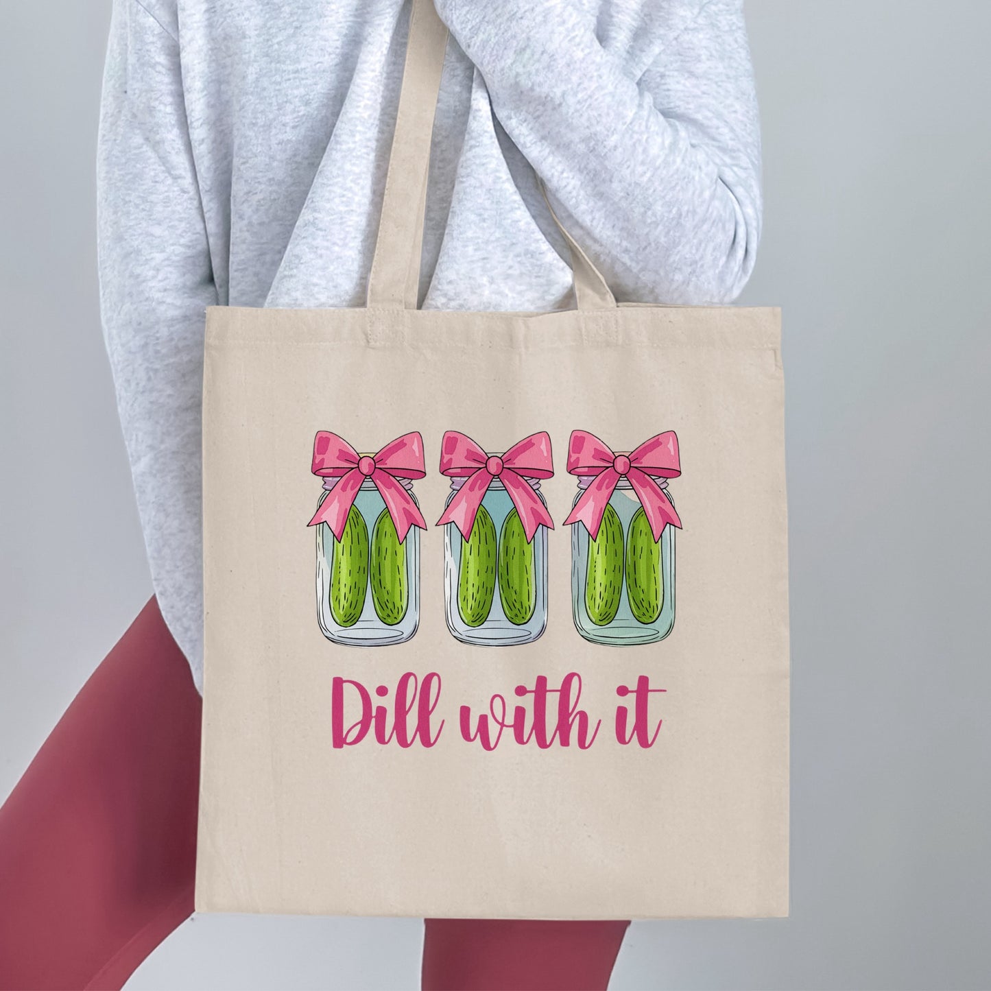Tote bag with three jars of pickles wearing bows, text "Dill with it".