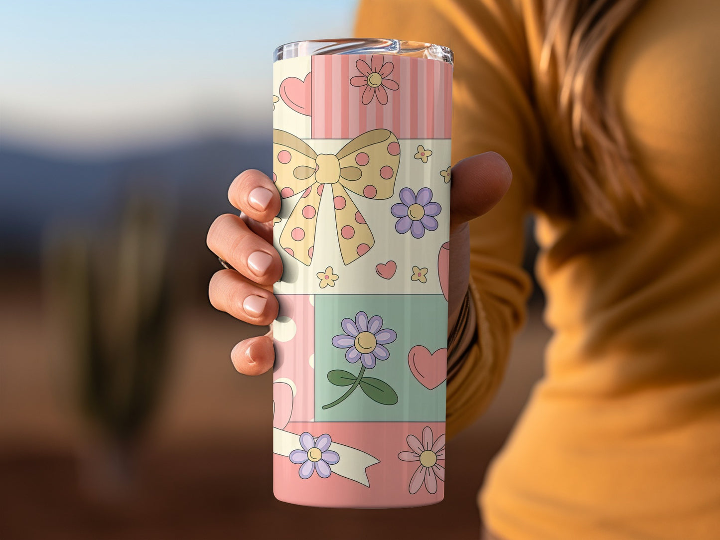 Pink and yellow patterned tumbler with bow, flowers, and hearts.