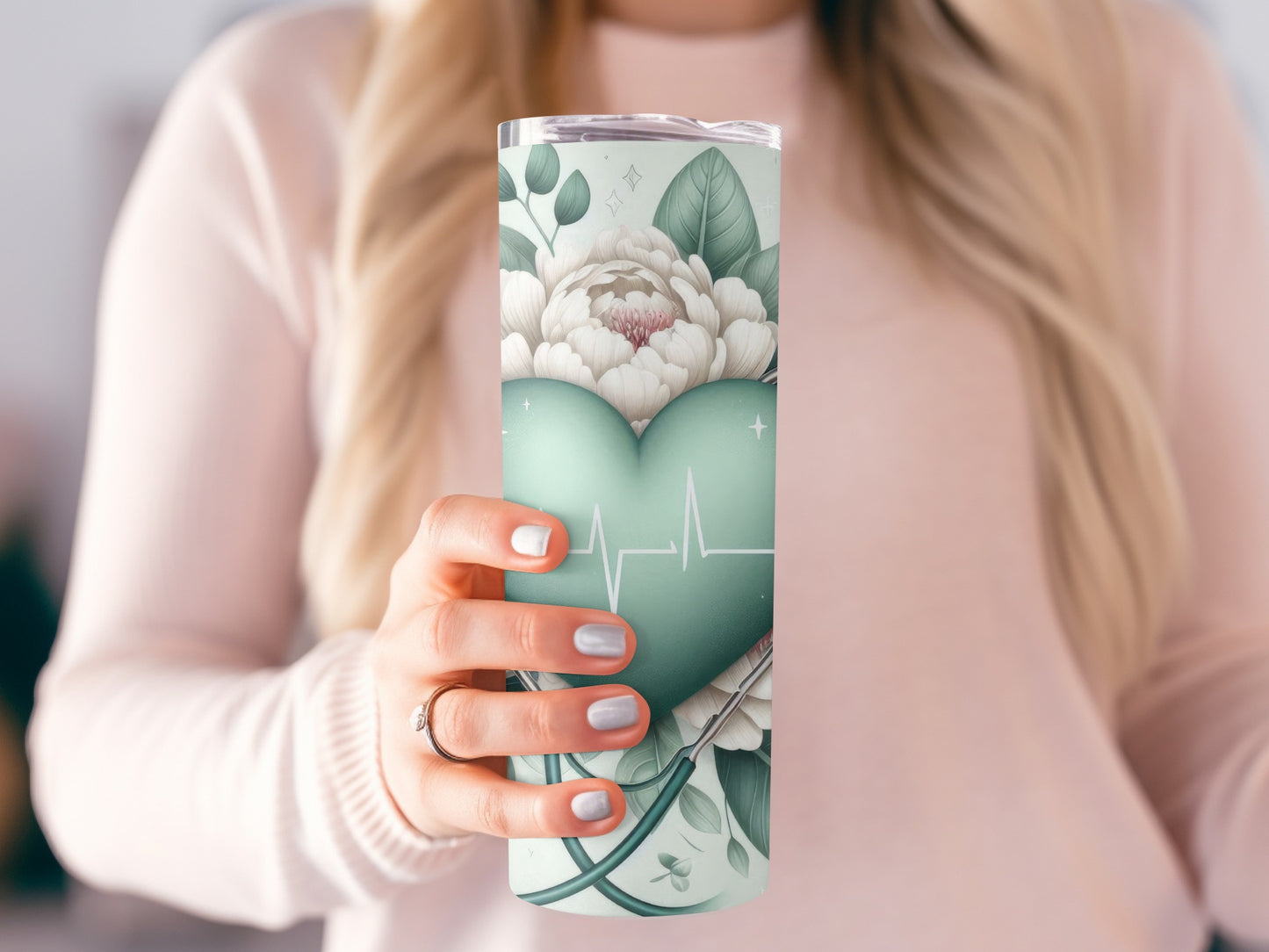 Woman holding a teal tumbler with floral and heart-shaped ECG design.
