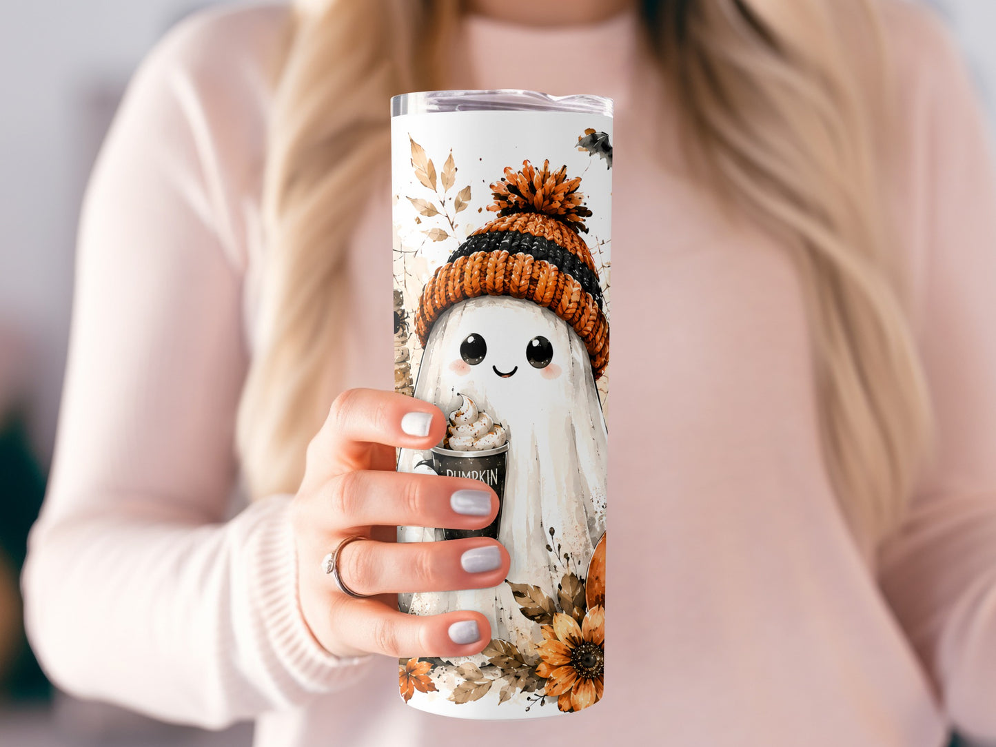 Tumbler with ghost wearing beanie holding pumpkin spice drink, autumn leaves and flowers.