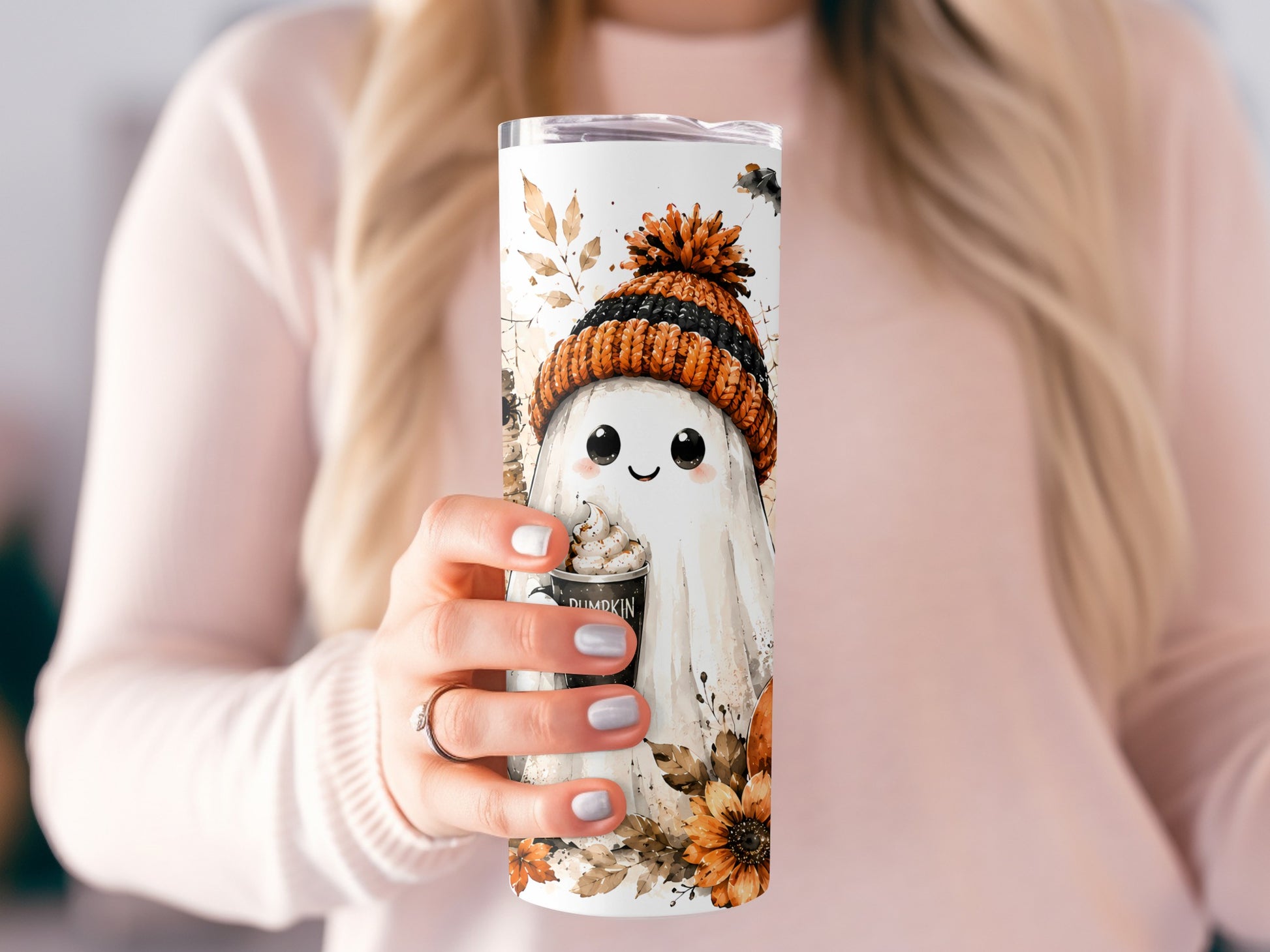 Tumbler with ghost wearing beanie holding pumpkin spice drink, autumn leaves and flowers.