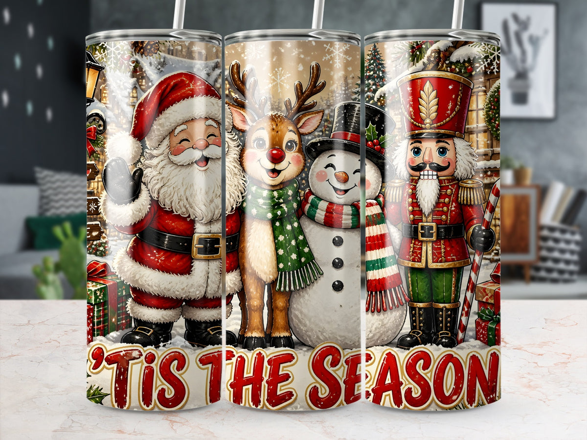 Three cylindrical tumblers stand side-by-side on a marble surface, displaying a continuous Christmas scene featuring Santa Claus, a reindeer, a snowman, a nutcracker, and the text Tis the Season.