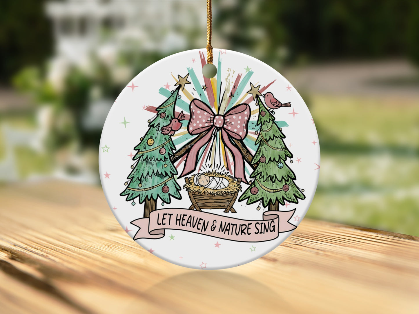 Christmas ornament with Nativity scene, trees, birds, and text "Let Heaven & Nature Sing".