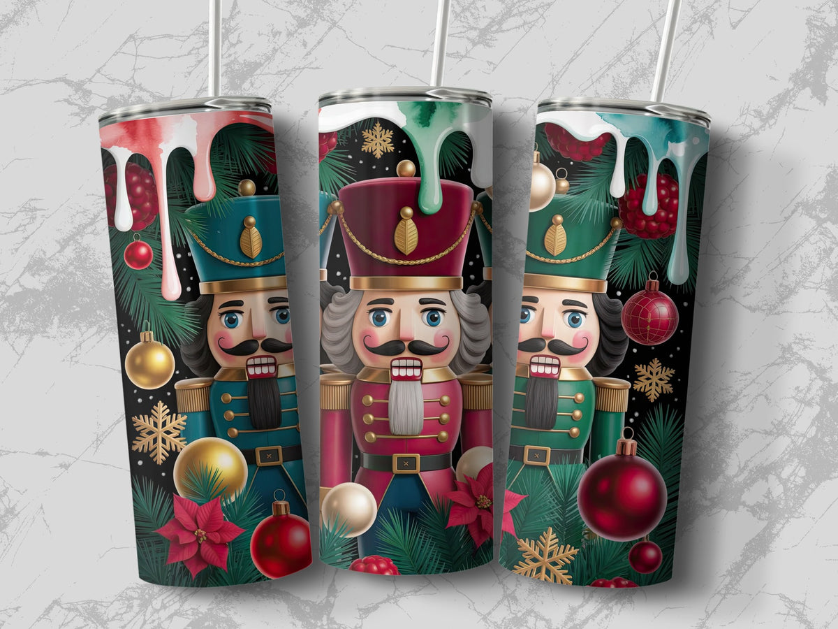Three metal tumblers with straws feature a Christmas nutcracker, pine branches, ornaments, and dripping paint designs.