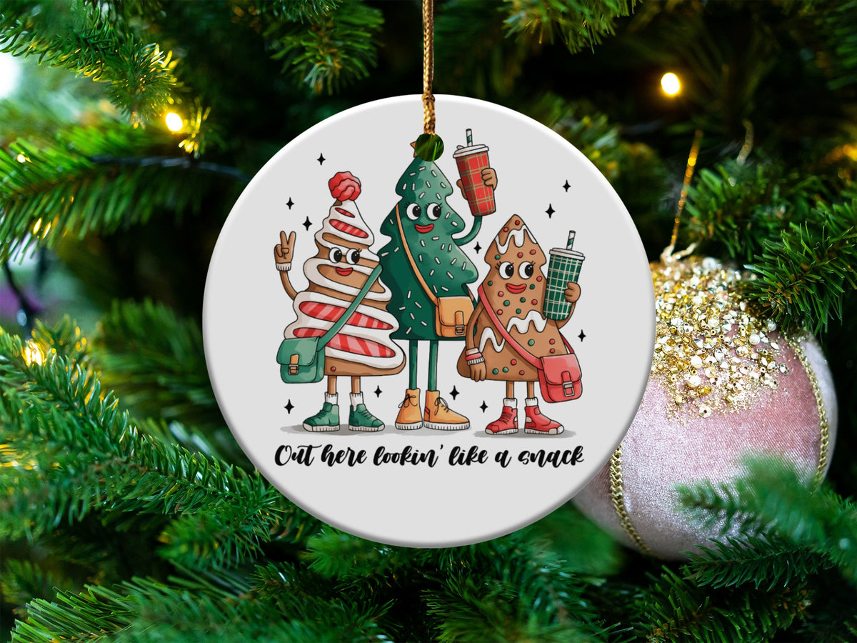Round ornament featuring three cartoon Christmas treats with text "Out here lookin' like a snack".