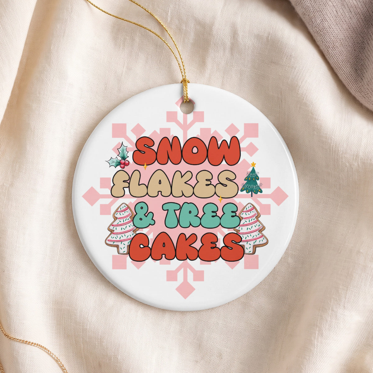 Round ceramic ornament with text "SNOW FLAKES & TREES CAKES" and holiday icons.