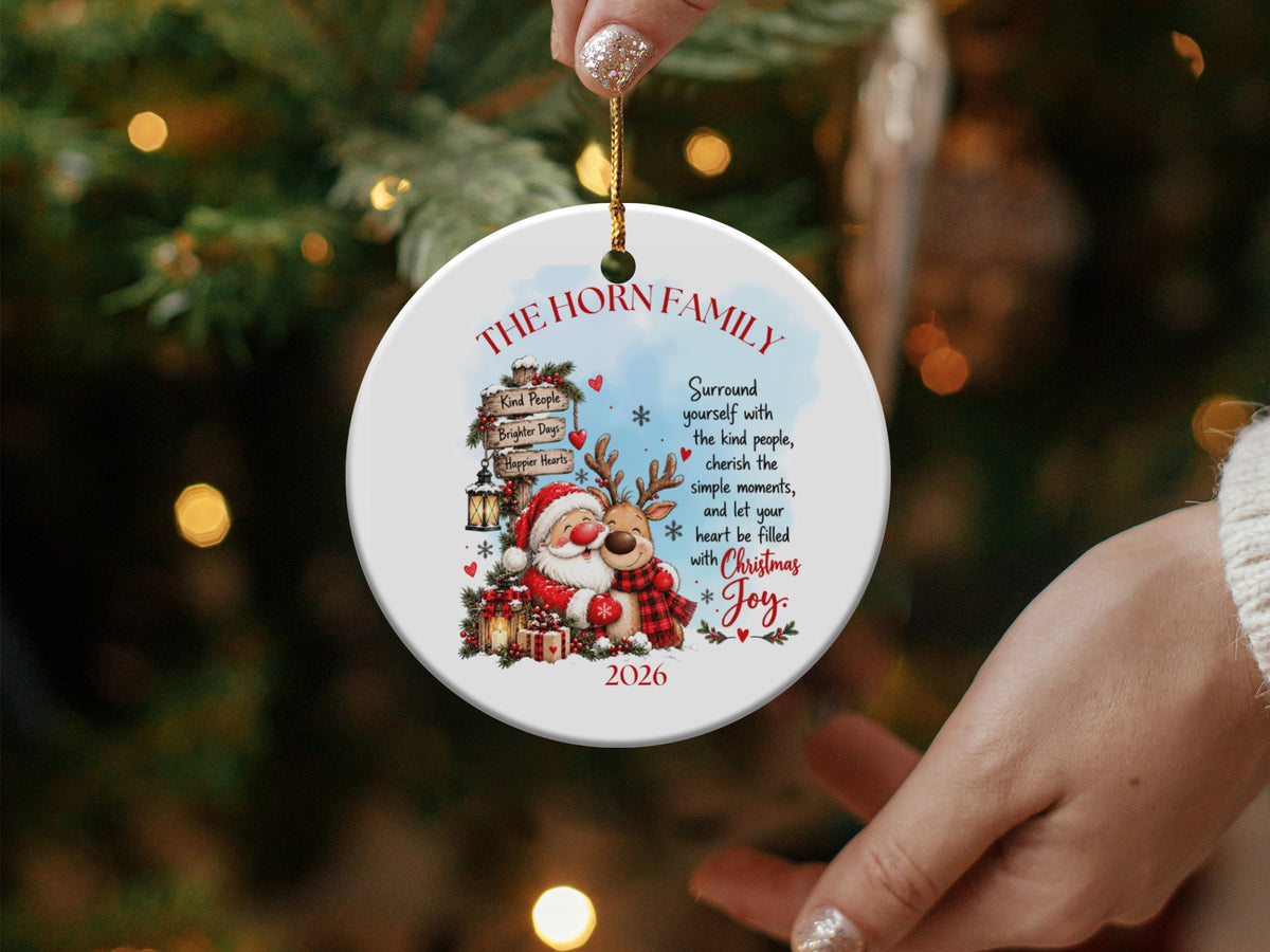 A round white ceramic Christmas ornament featuring Santa, a reindeer, a directional sign, and inspirational text.