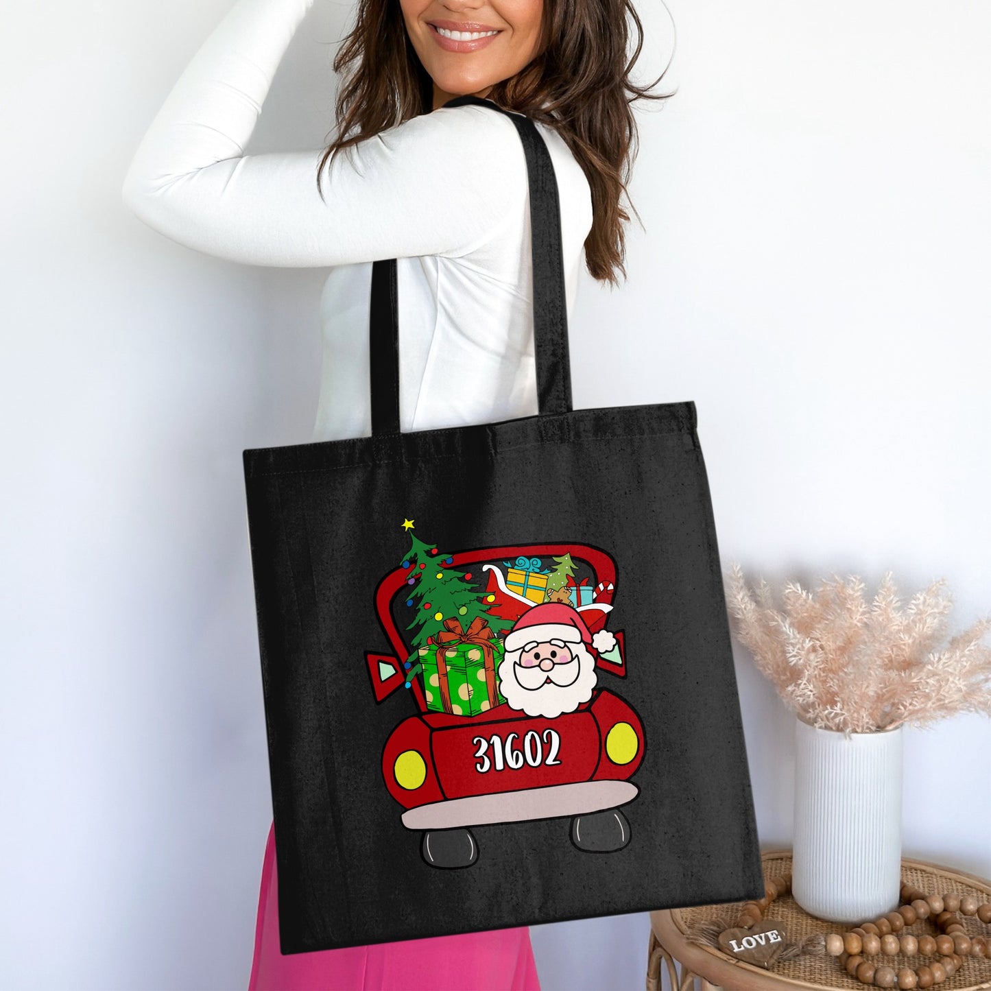 Black tote bag with Santa in a red truck with gifts and a Christmas tree graphic.