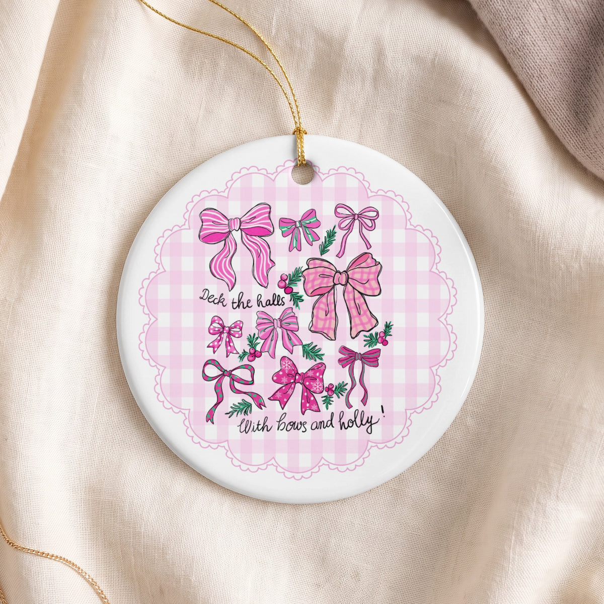 Round ornament with pink bows and holly design, reads "Deck the halls with bows and holly!".