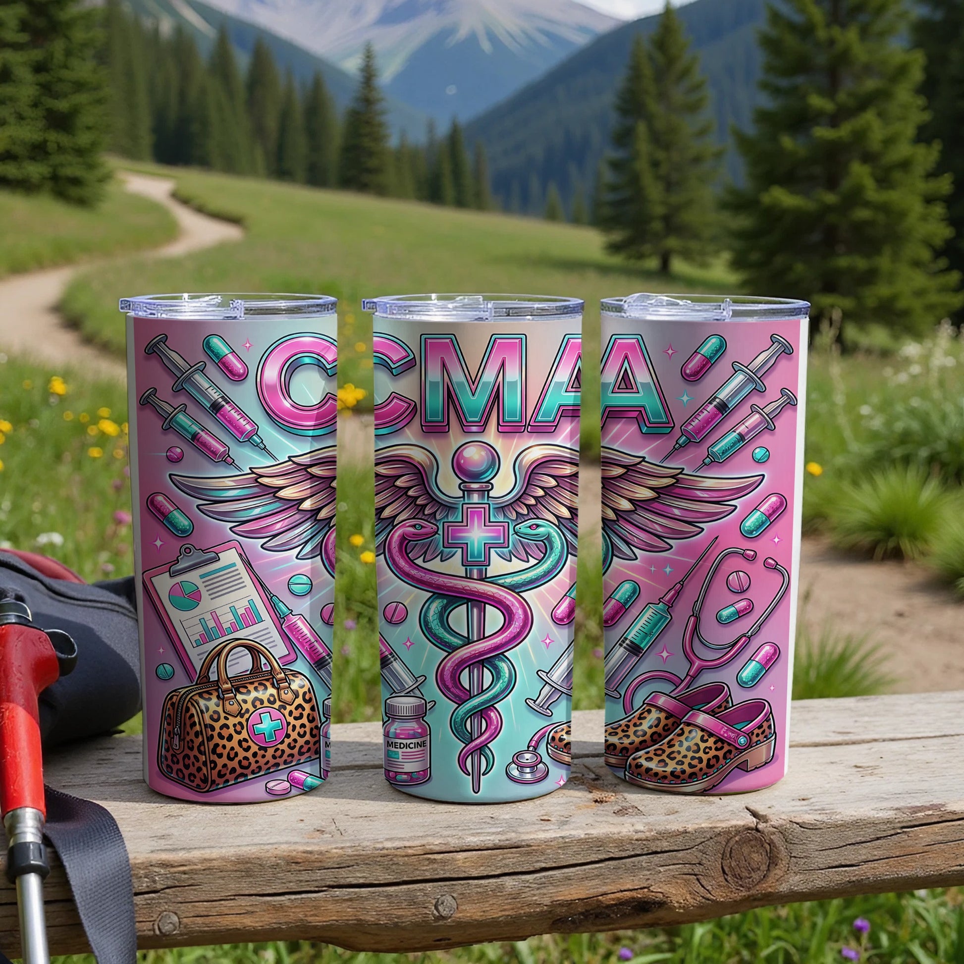 Three tumblers with CMAA logo and medical icons, set on a wooden table outdoors.