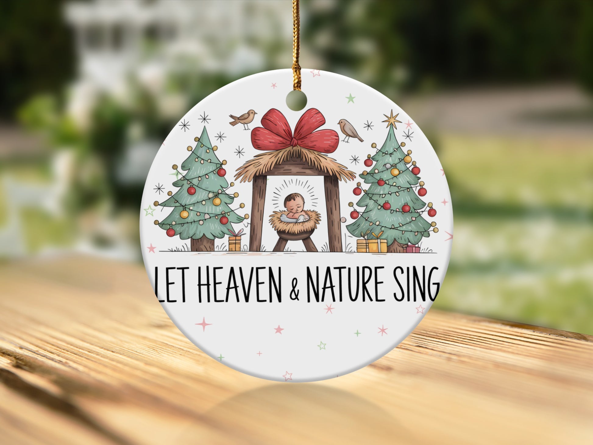Nativity scene ornament with two Christmas trees and the text "LET HEAVEN & NATURE SING".