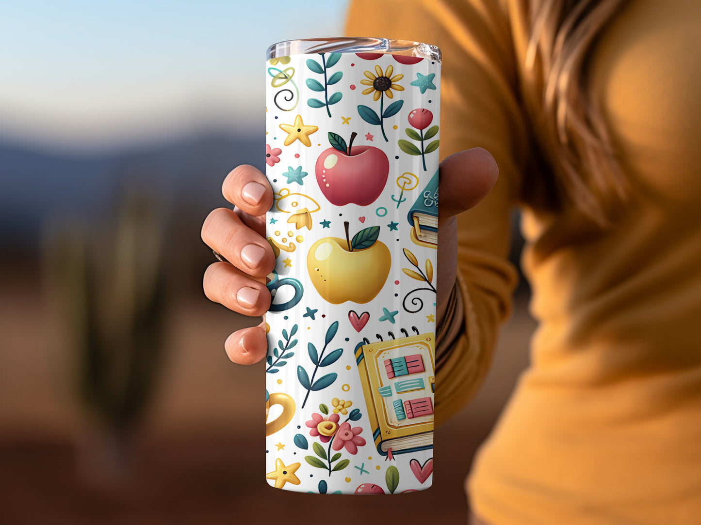 Tumbler with white background featuring apples, books, flowers, and stars design.