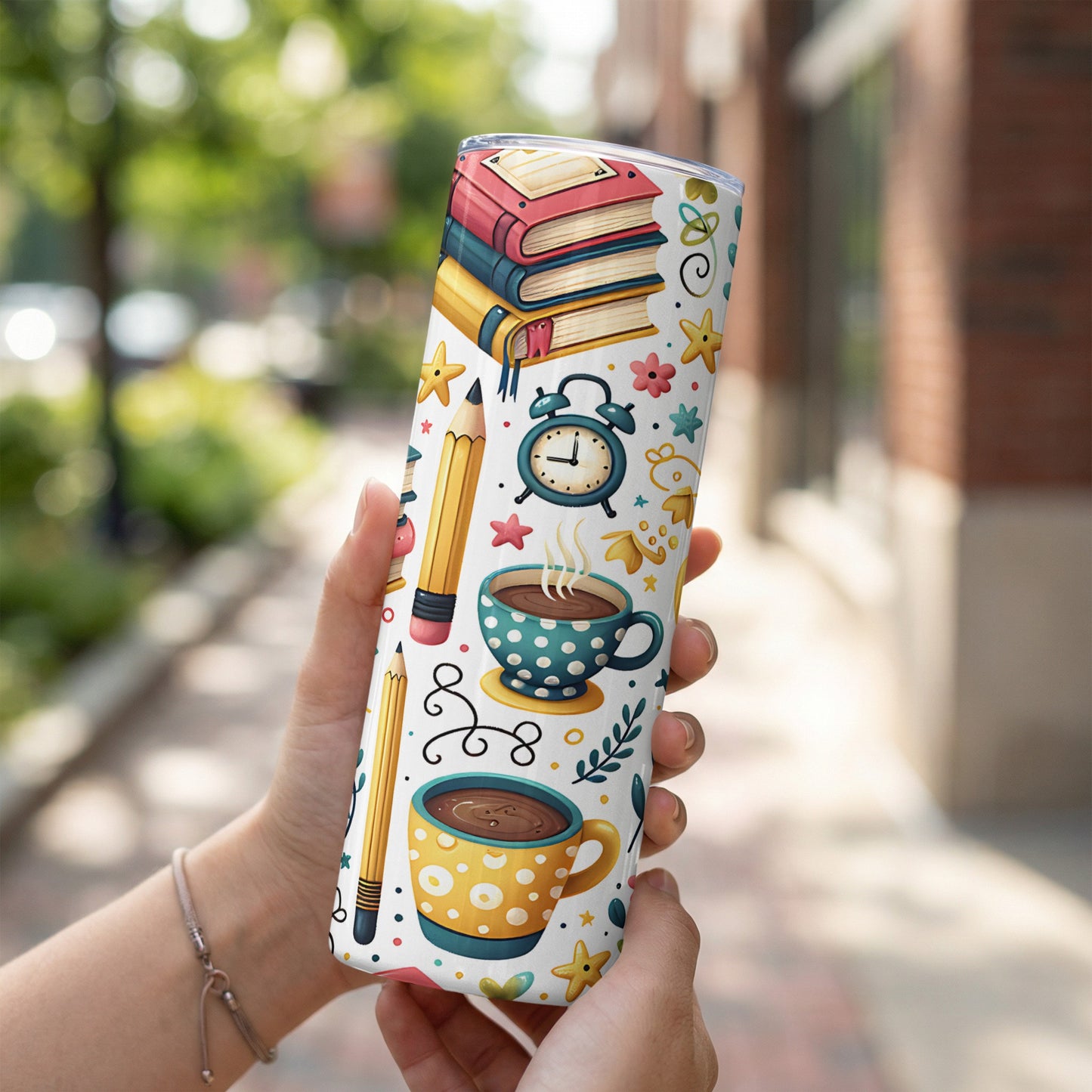 Tumbler with stacked books, coffee cups, pencils, and alarm clock pattern.