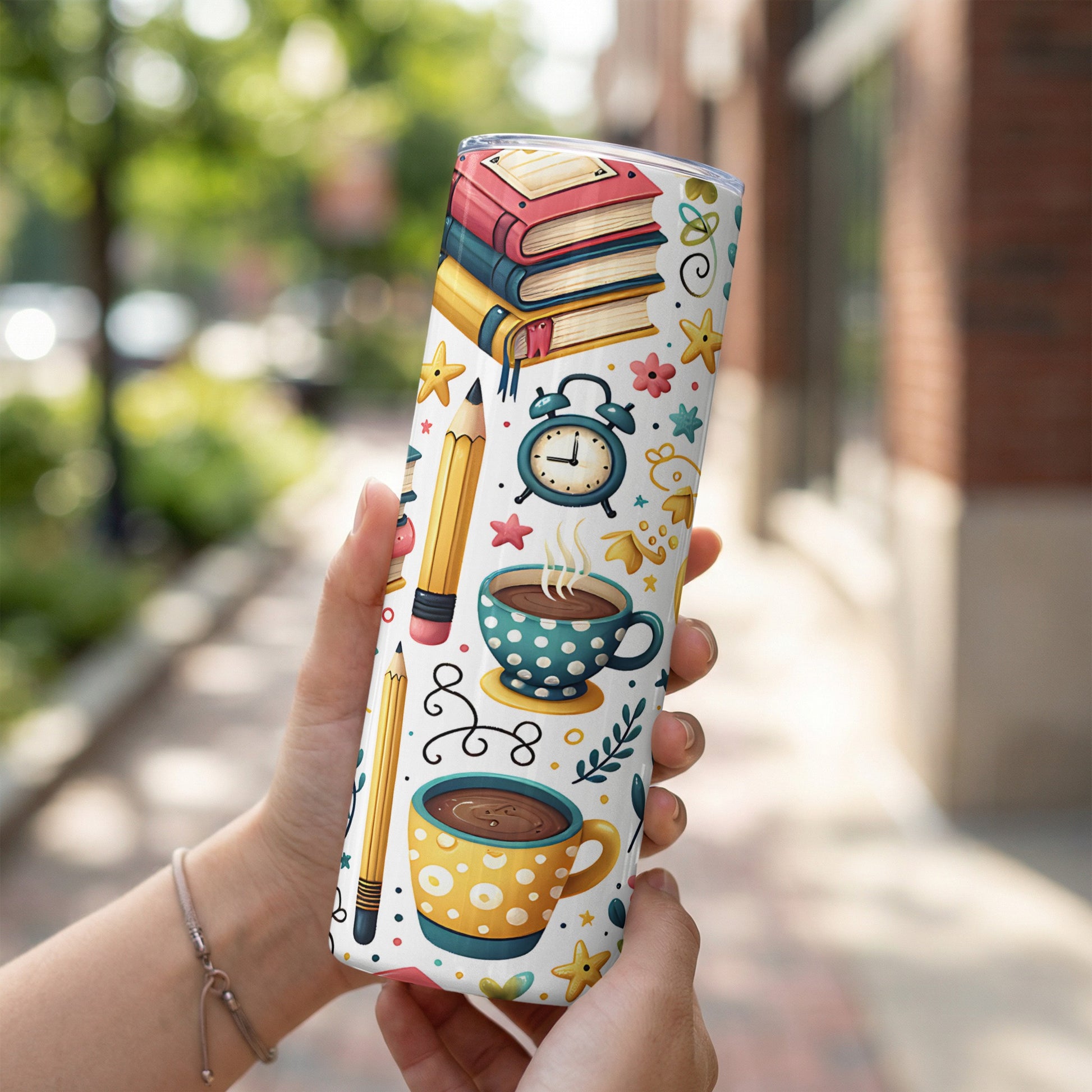 Tumbler with stacked books, coffee cups, pencils, and alarm clock pattern.