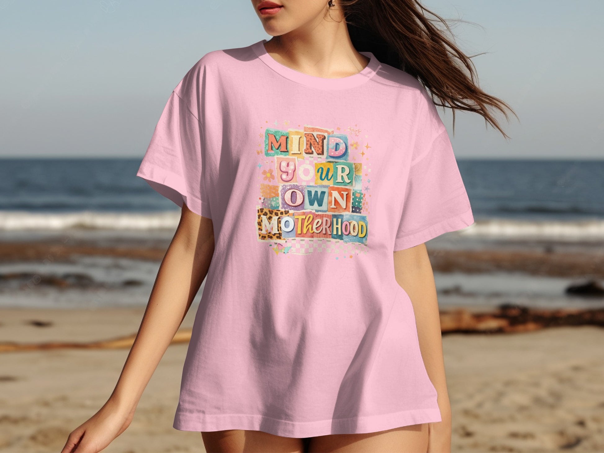 Pink t-shirt with "Mind Your Own Motherhood" text in colorful, varied fonts.