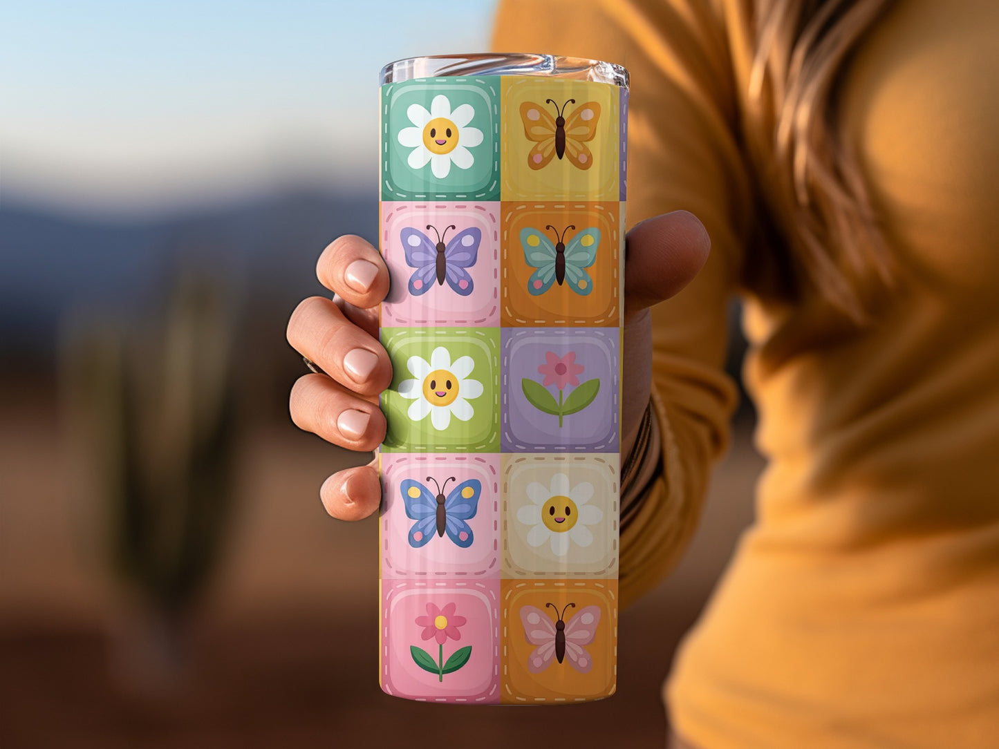 Floral and butterfly tile pattern on a tumbler held by a person.