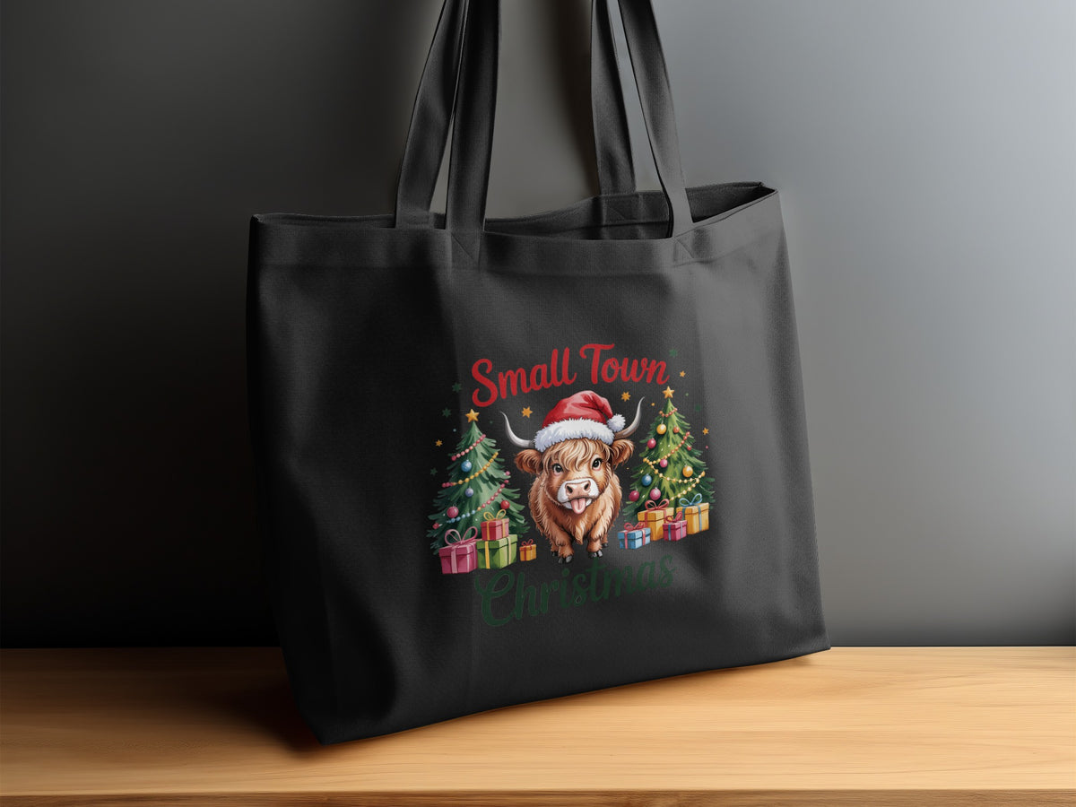 Black tote bag with "Small Town Christmas" and a highland cow in Santa hat.