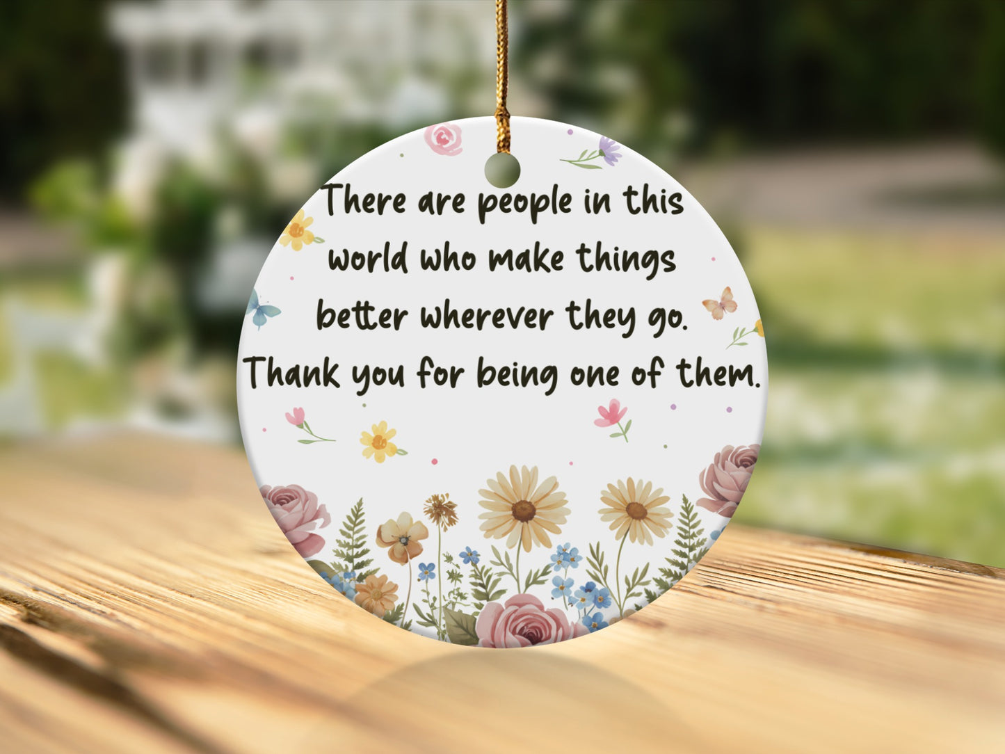 Round ceramic ornament with floral design and quote.