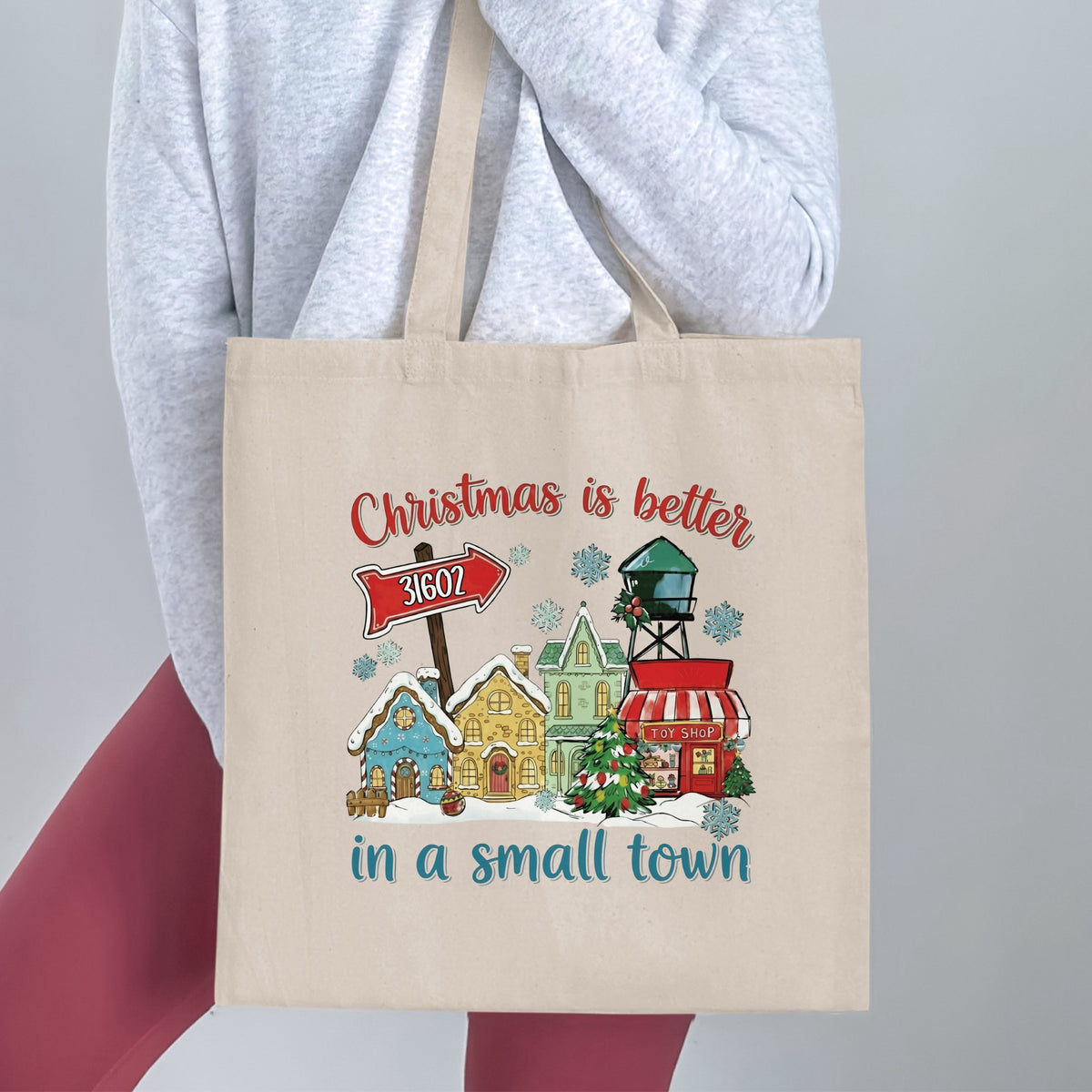 Tote bag with a Christmas town scene and the text "Christmas is better in a small town".