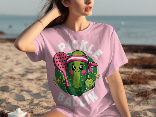 Pink t-shirt with cartoon pickle, tennis racket, and ball graphic.