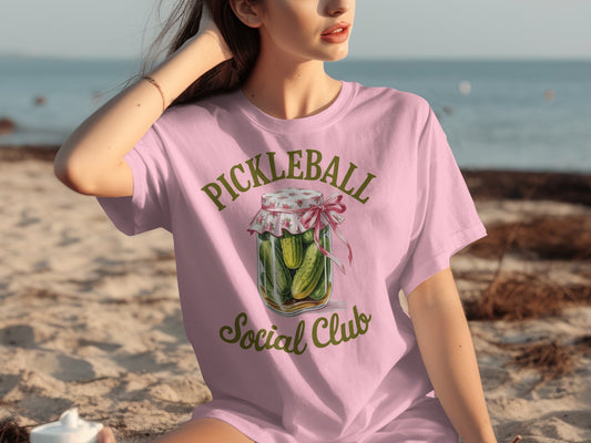 Pink t-shirt with a pickle jar graphic and "Pickleball Social Club" text.