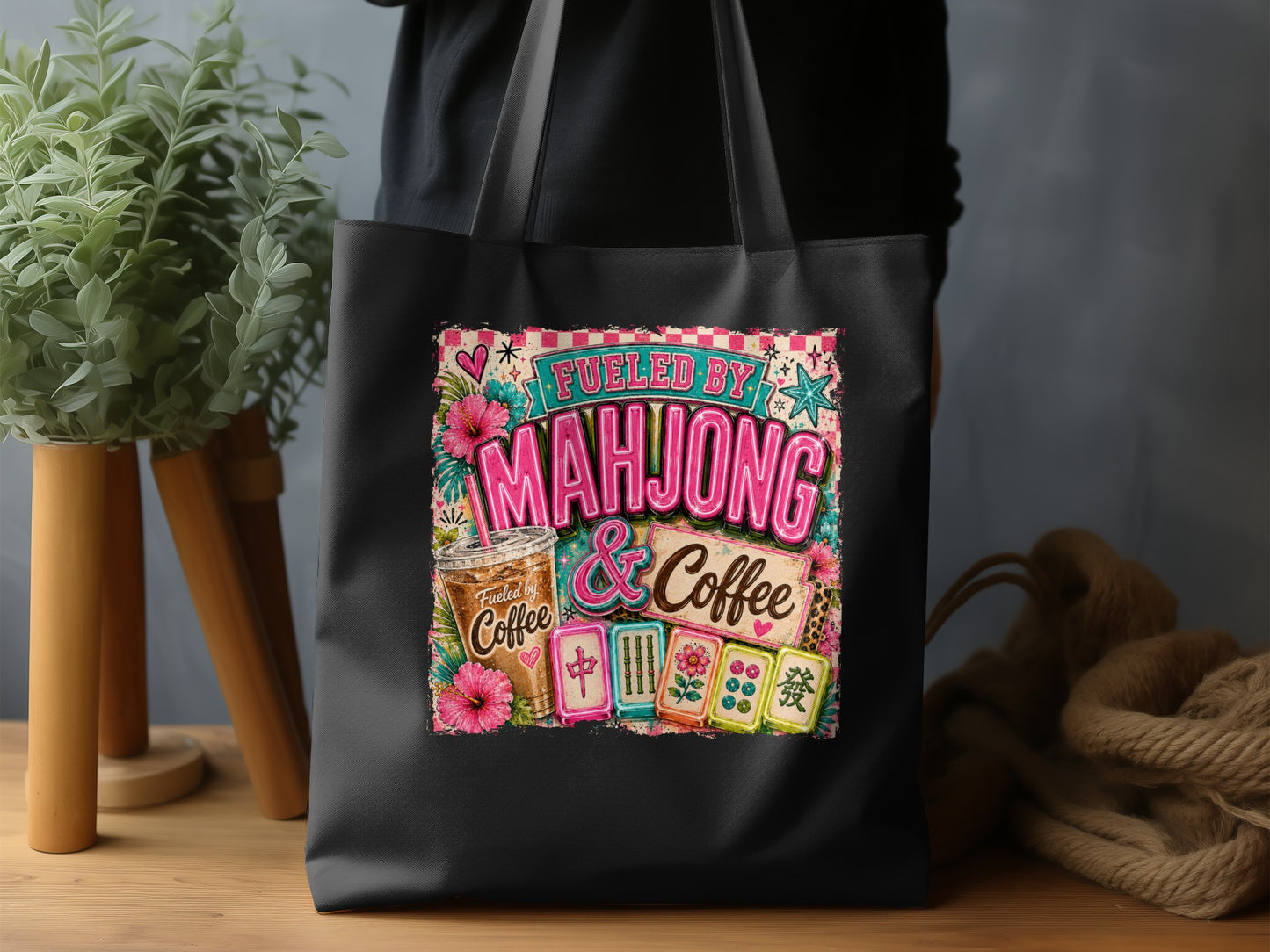 Black tote bag with "Fueled by Mahjong & Coffee" graphic and mahjong tiles.