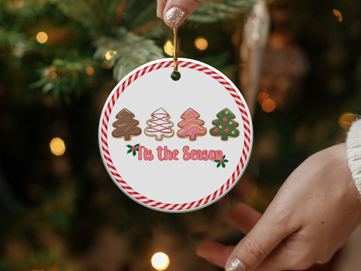 Round ceramic ornament with four decorated Christmas tree cookies and "Tis the Season" text.