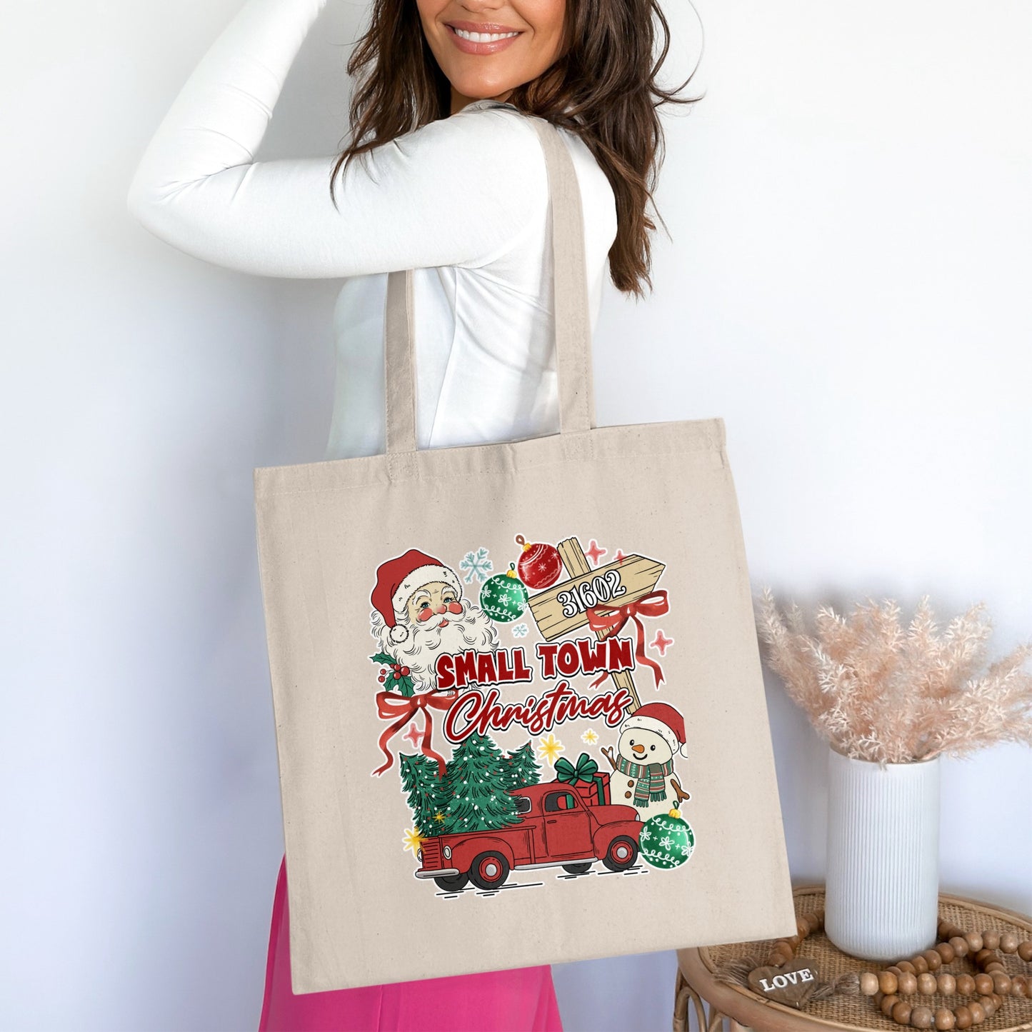 Tote bag with Christmas design featuring Santa, snowman, truck, trees, and "Small Town Christmas" text.