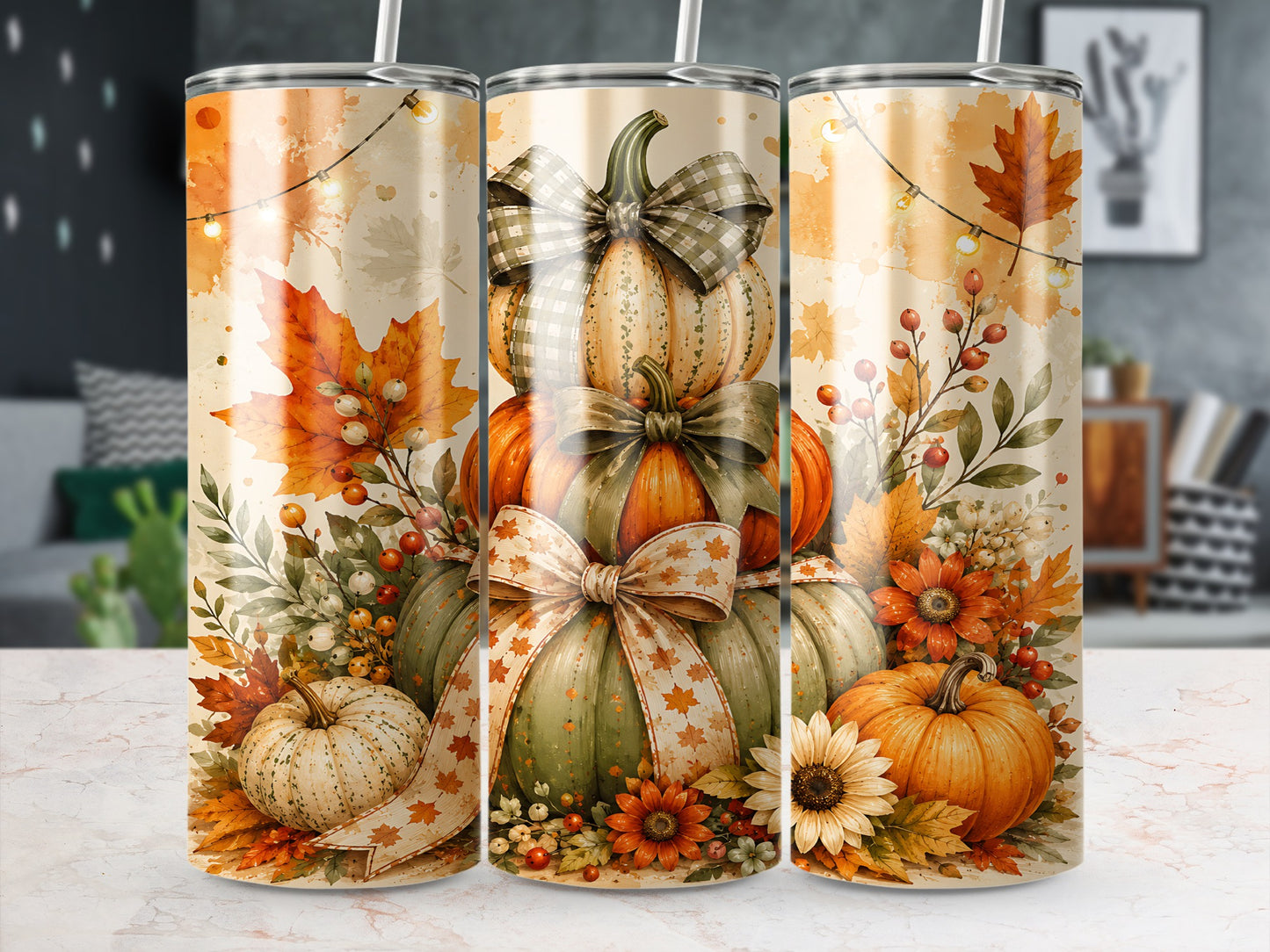 Three tumblers with stacked pumpkins, autumn leaves, flowers, and string lights.