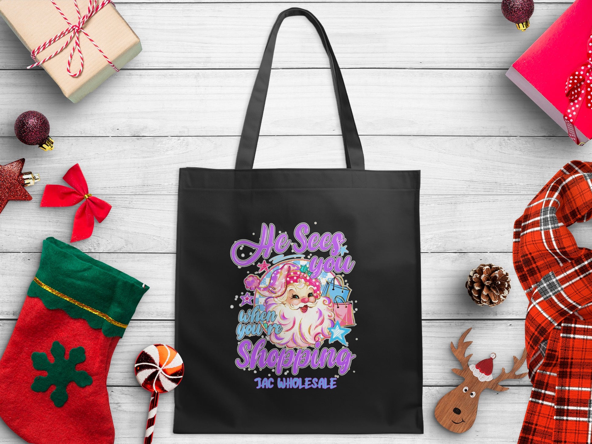 Black tote bag with Santa graphic: "He Sees You When You're Shopping."