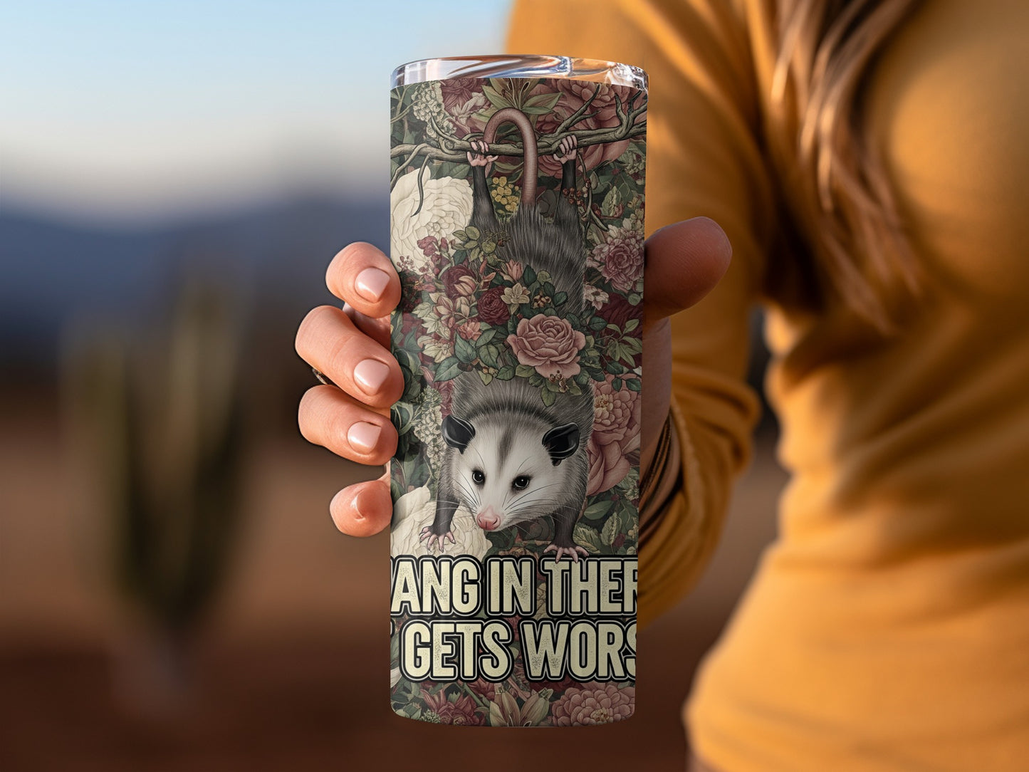 Opossum hanging upside down with floral design and text.