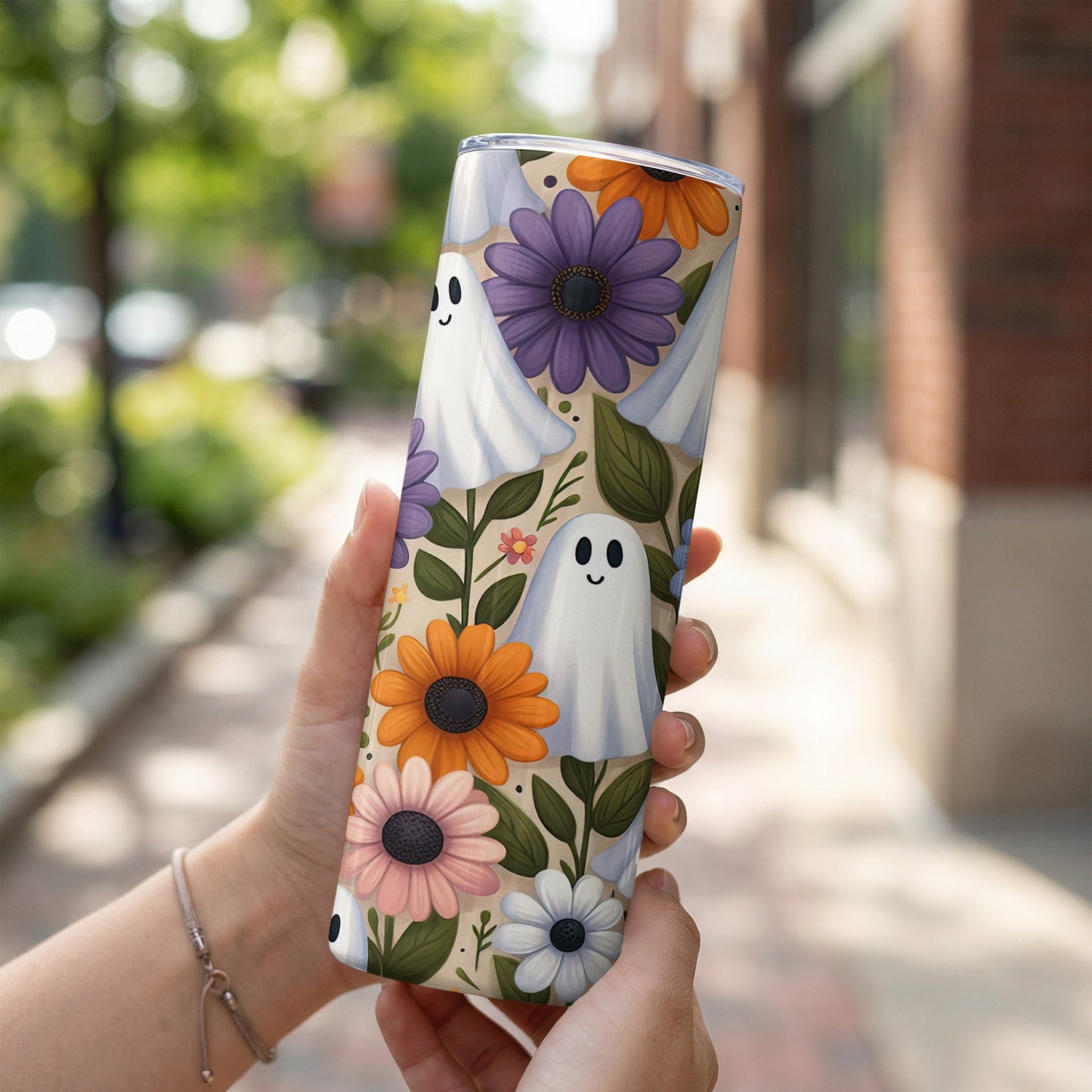 Tumbler with cartoon ghosts and colorful flowers on a light background.