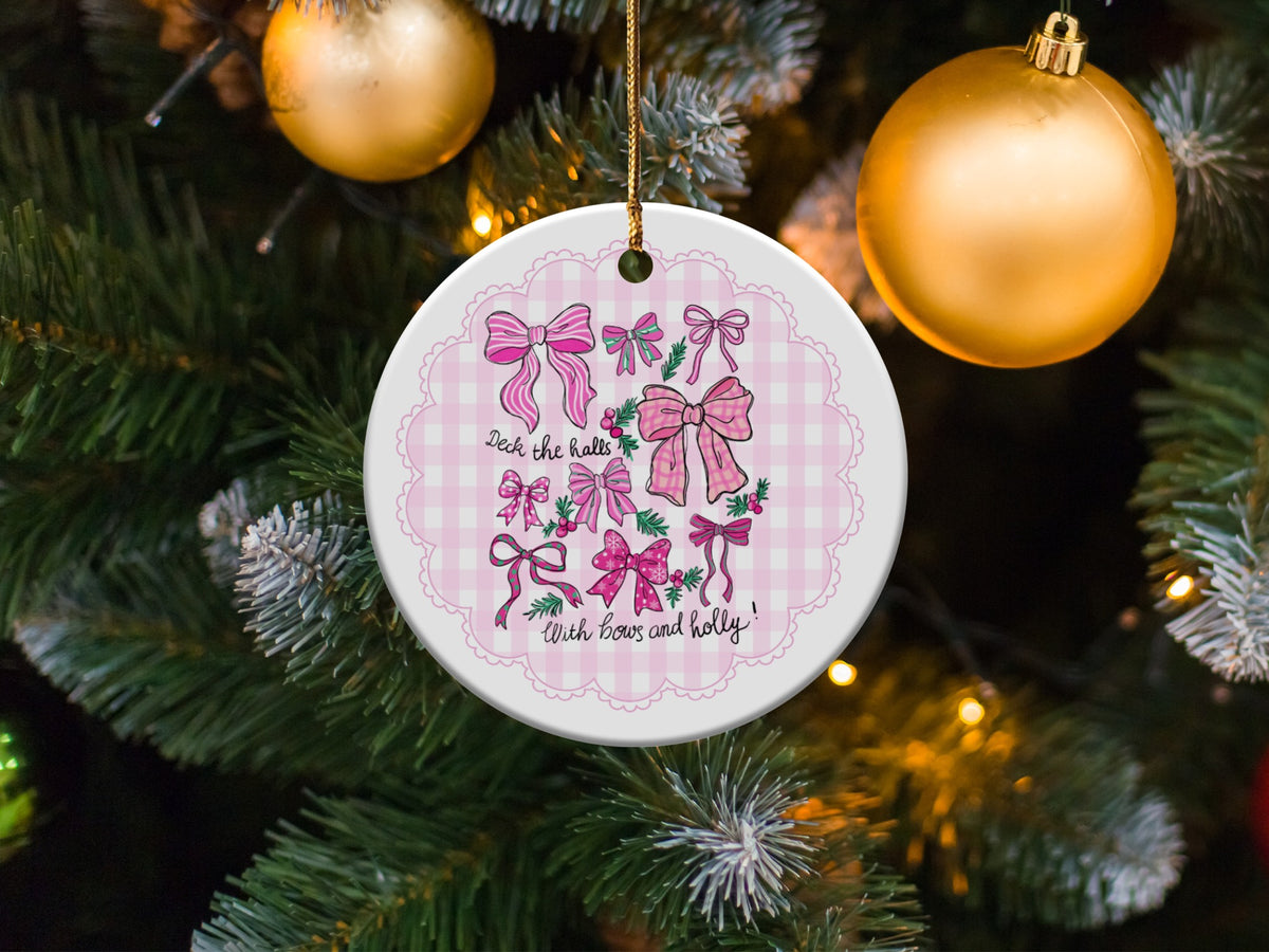 Christmas ornament with pink bows and holly, says "Deck the halls with bows and holly."