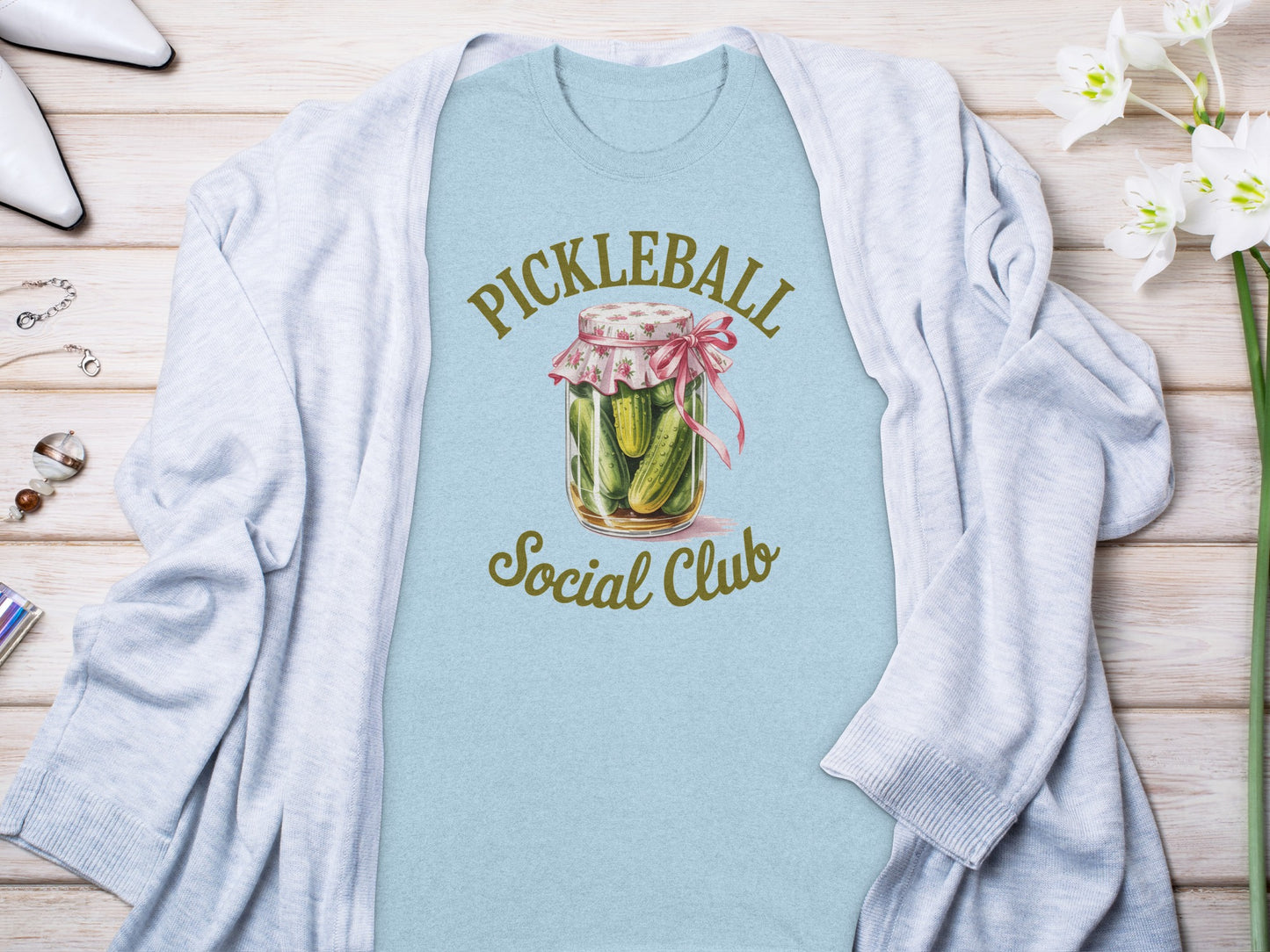 Light blue t-shirt with "Pickleball Social Club" in a pickle jar graphic.