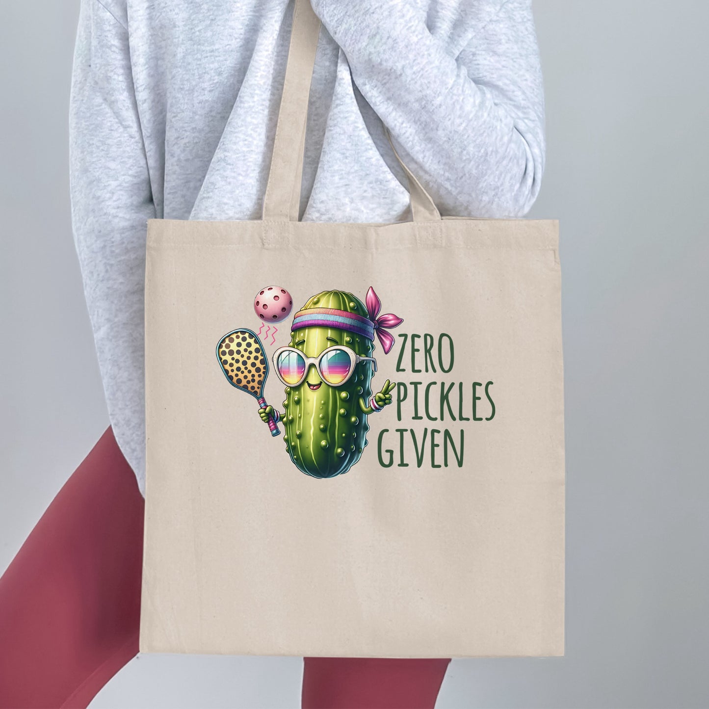 Canvas tote bag with a cartoon pickle playing pickleball, wearing sunglasses and a headband, with "Zero Pickles Given" text.