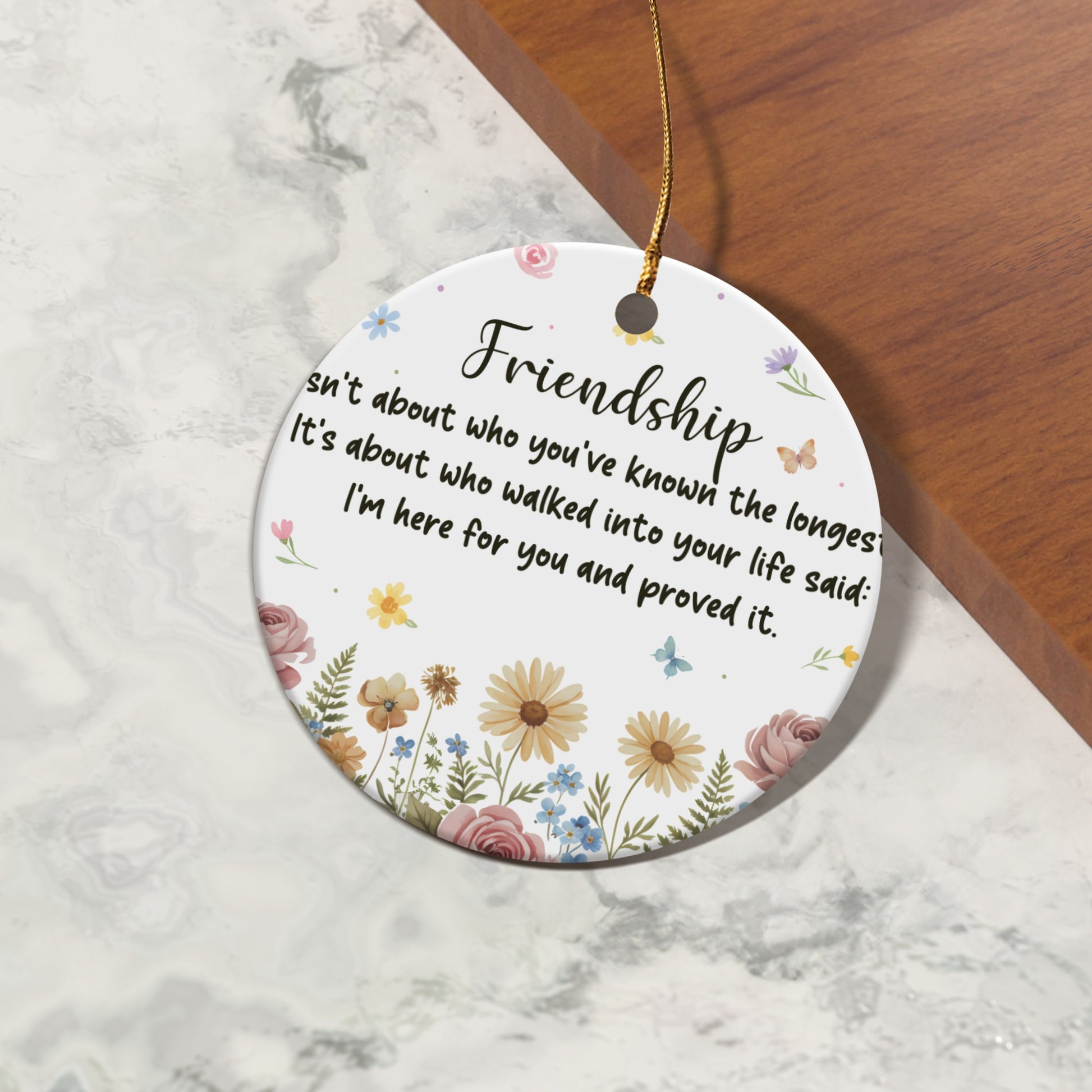 Round ceramic ornament with friendship quote and floral design.