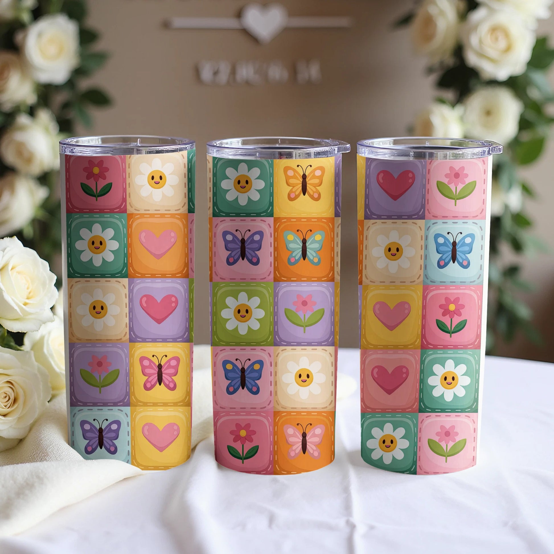 Three tumblers with a pastel square pattern of flowers and butterflies.