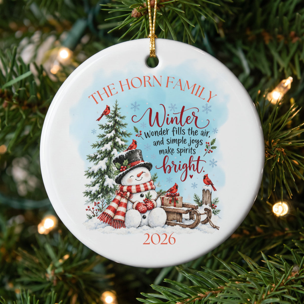 Round white ceramic Christmas ornament featuring a snowman, pine tree, red cardinals, and text.