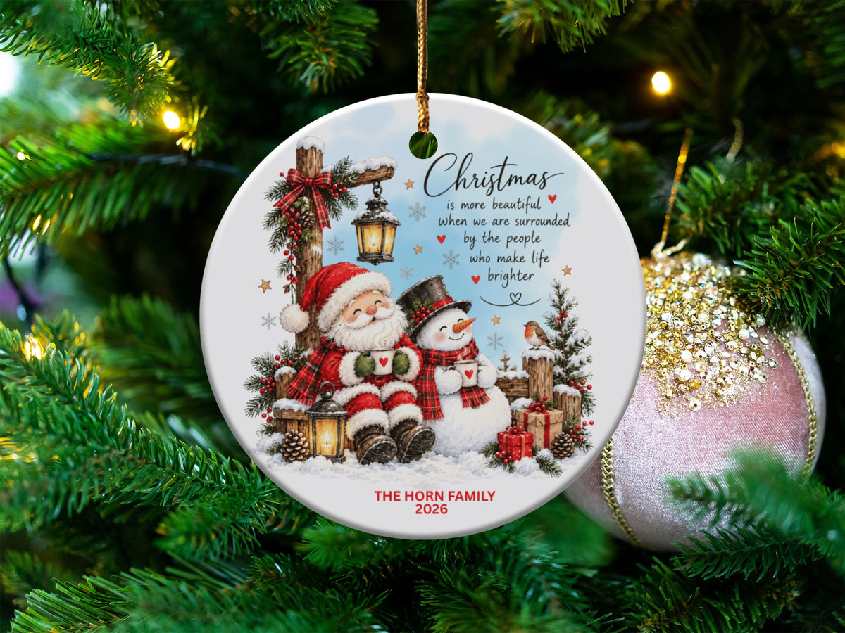 Round ceramic Christmas ornament featuring Santa and a snowman holding mugs, with personalized text.
