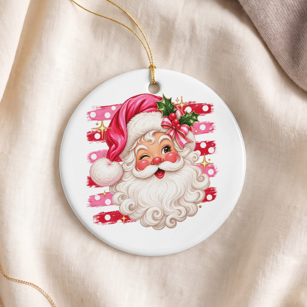 Winking Santa Claus face ornament with pink hat and holly on striped background.
