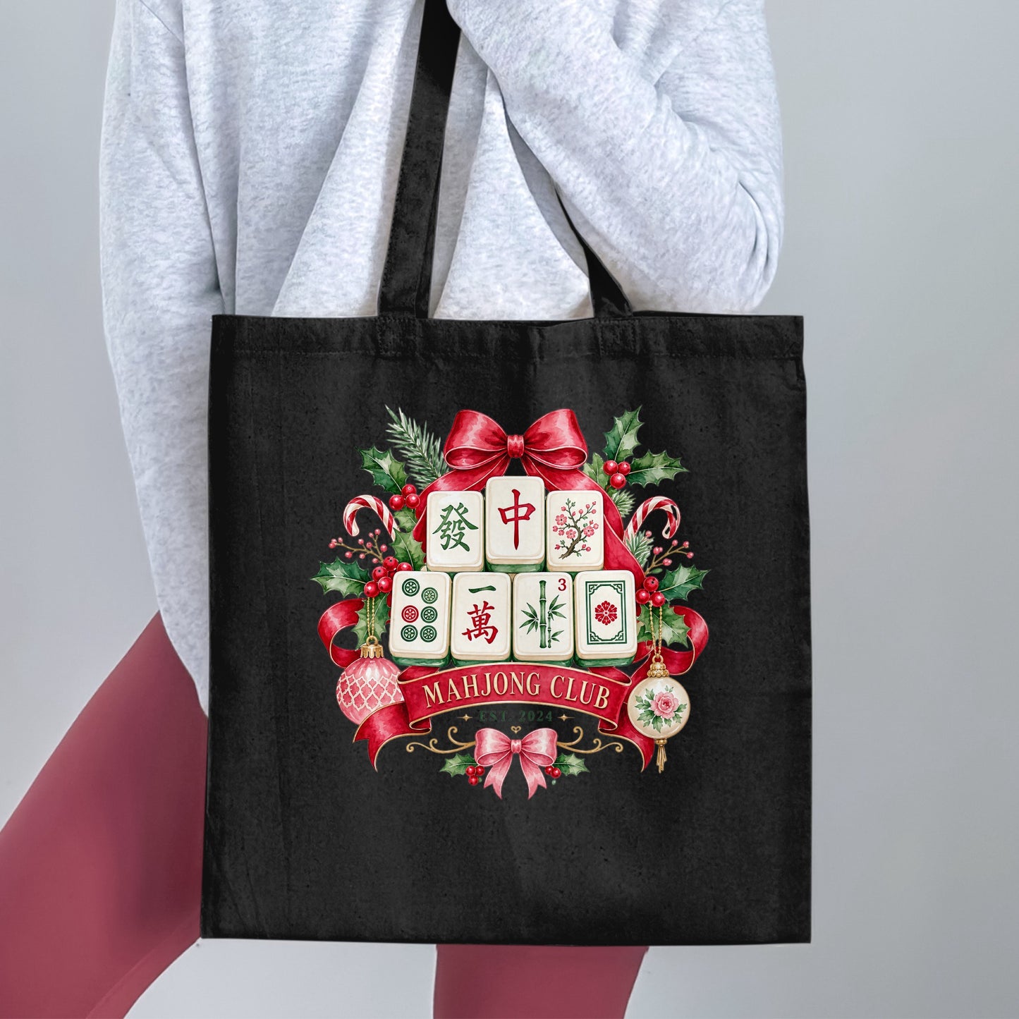 Black tote bag with festive mahjong tiles, ribbon, and ornaments graphic and text.