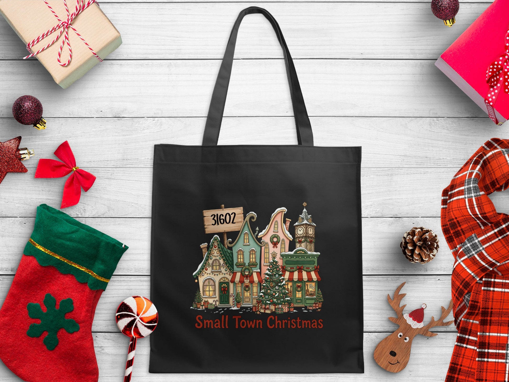 Black tote bag with a "Small Town Christmas" design featuring houses, a clock tower, and a Christmas tree.