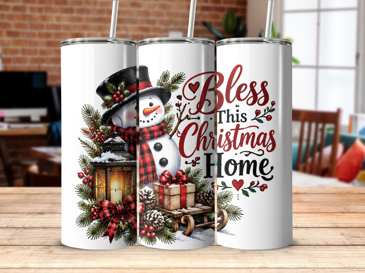 Three white skinny tumblers with straws feature a snowman, lantern, wrapped gifts, pine branches, and text reading Bless This Christmas Home.