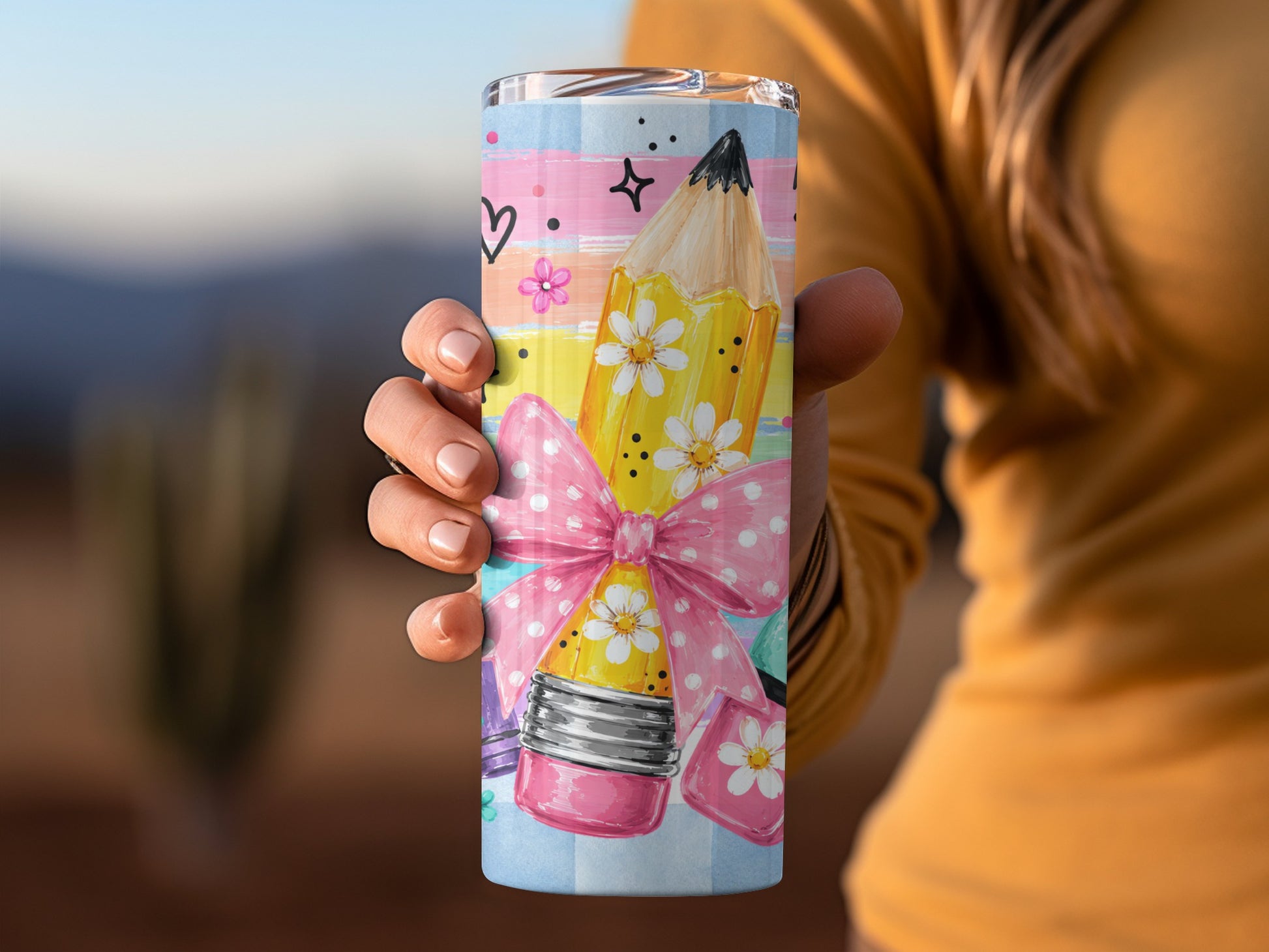 Tumbler with a pencil design, pink bow, and pastel stripes.