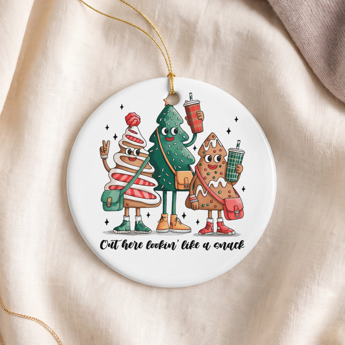 Christmas ornament featuring three cartoon gingerbread and tree characters holding drinks.