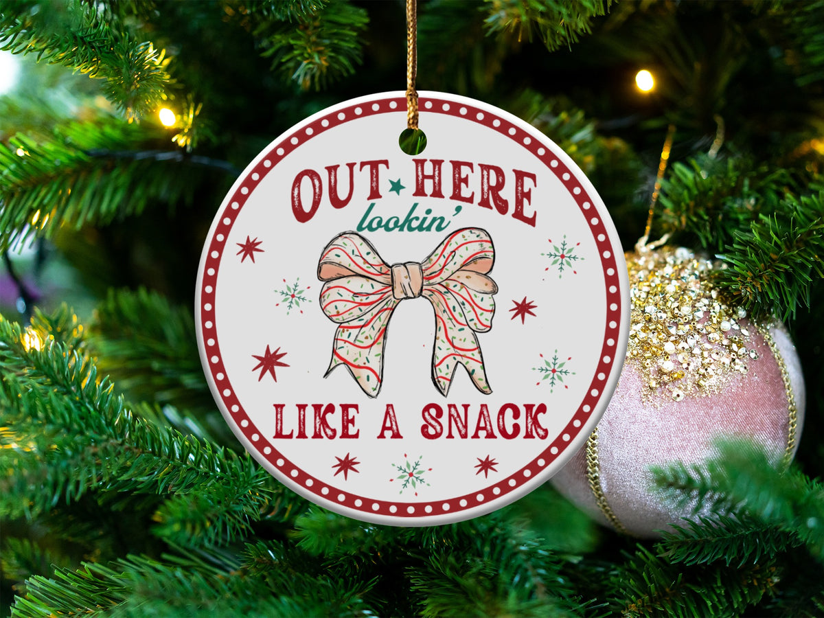 Round ornament with bow illustration and text "OUT HERE lookin' LIKE A SNACK".