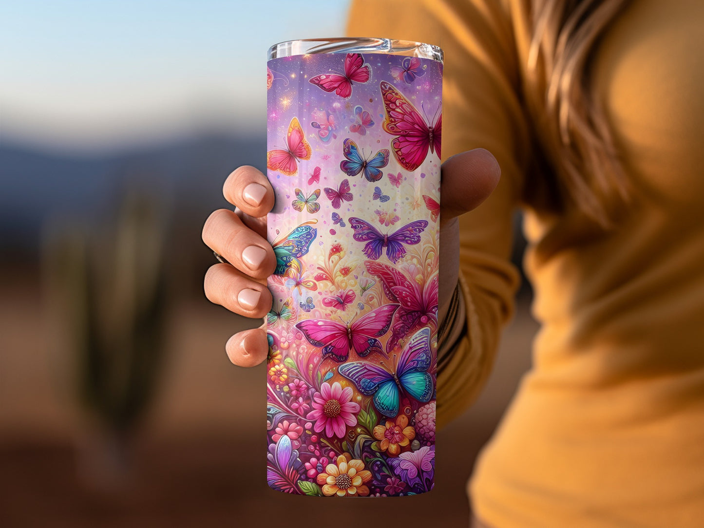 Woman holding a colorful tumbler with butterflies and flowers.