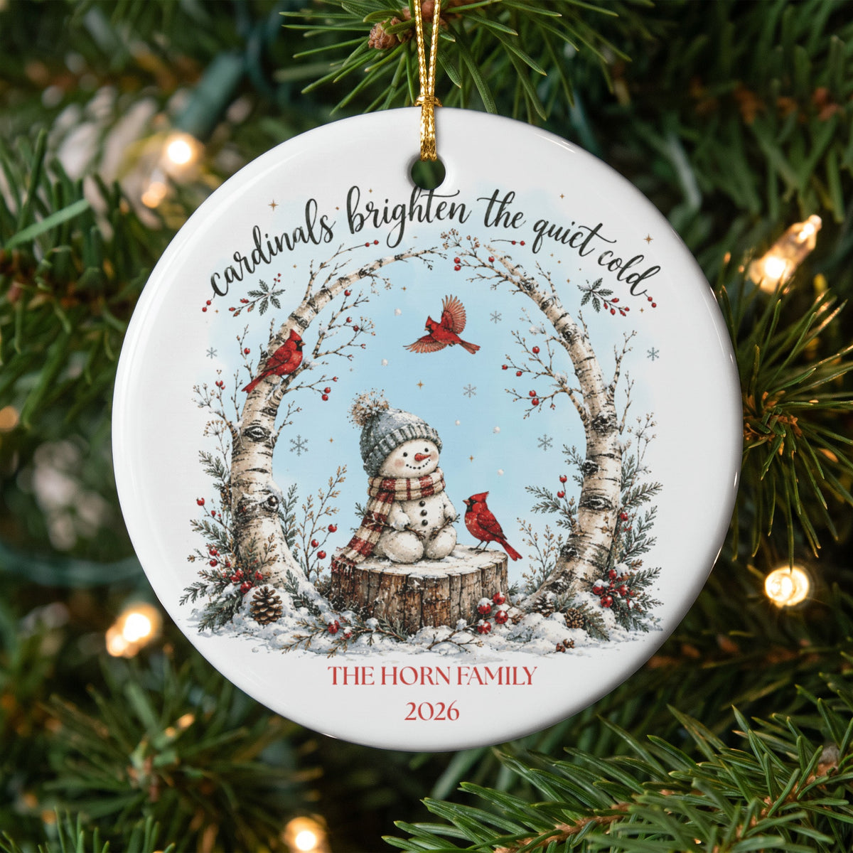 Round ceramic Christmas ornament featuring a snowman, red cardinals, birch trees, and personalized text.