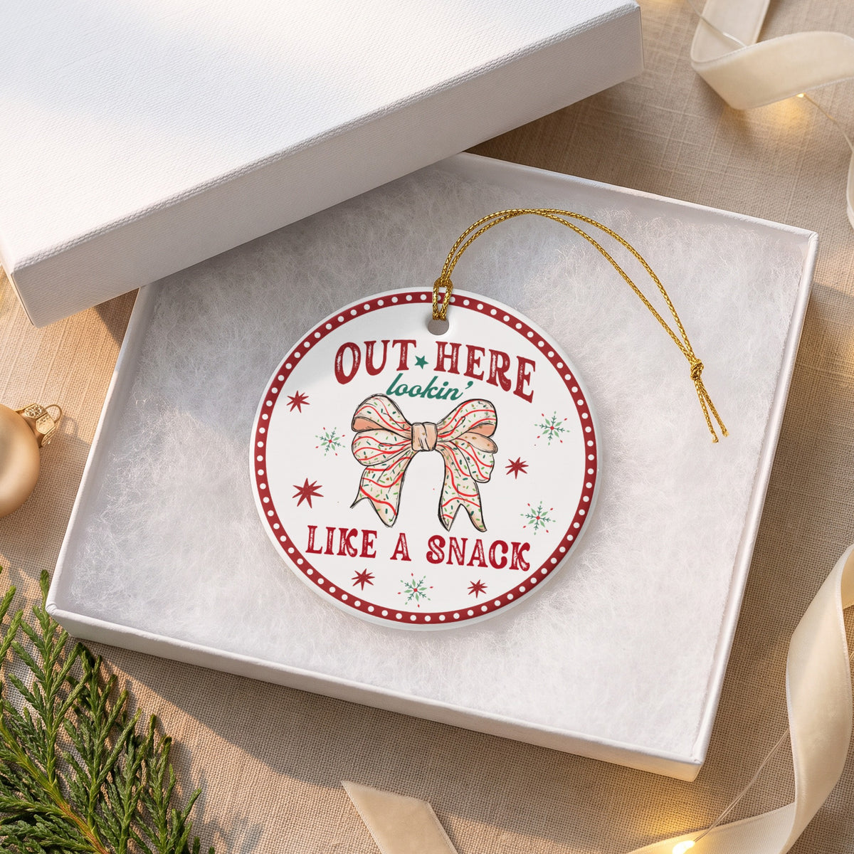 Ornament with text "OUT HERE lookin' LIKE A SNACK" and a bow.